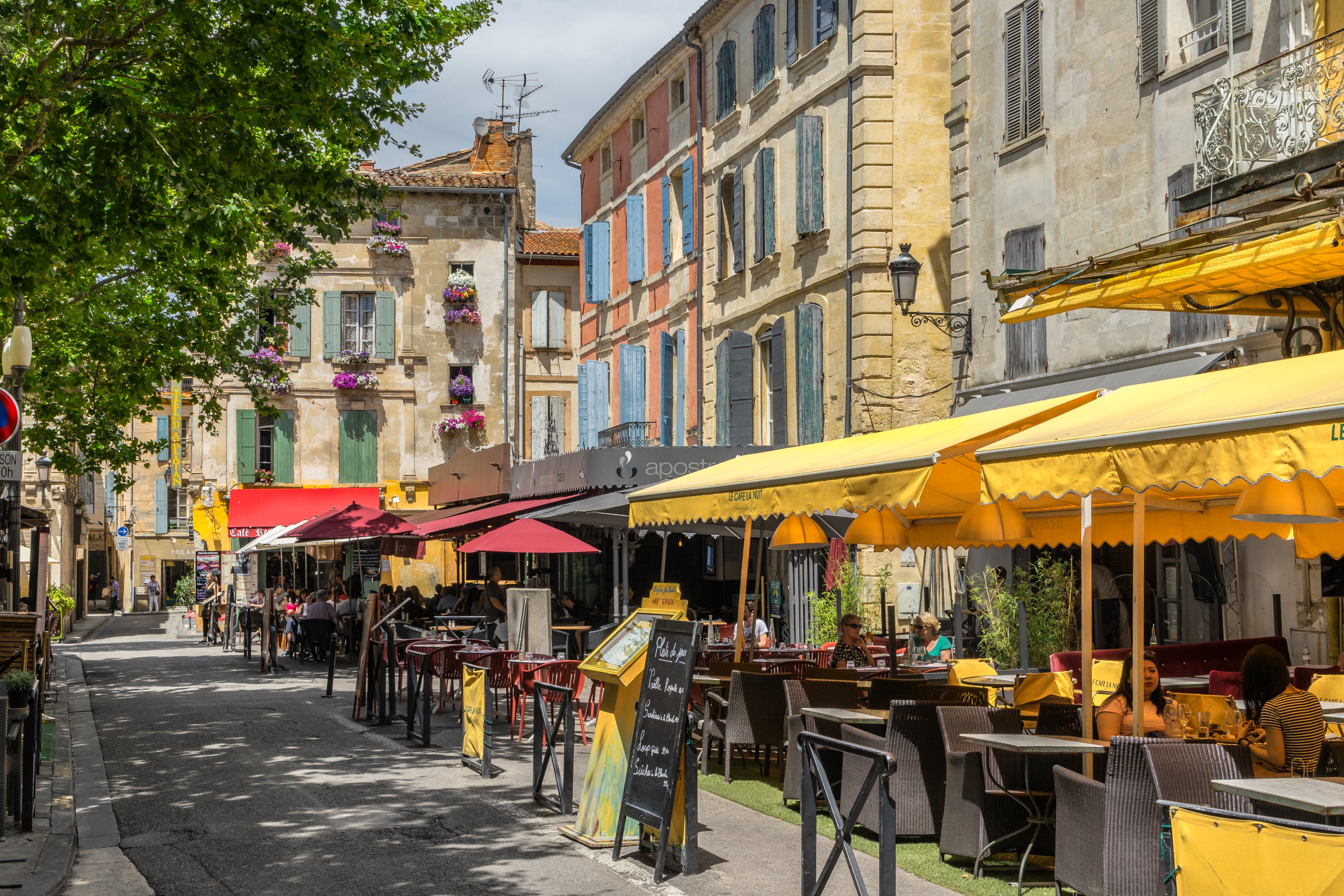 Sun-washed shutters and golden café awnings paint the scene at Place du Forum in Arles — the very square that inspired Van Gogh’s “Café Terrace at Night.
