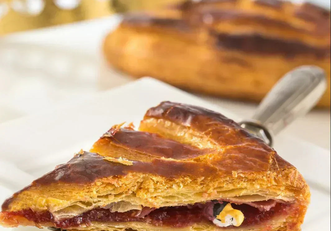 A slice of French galette des rois or king cake with crown and fève showing in the cake slice.